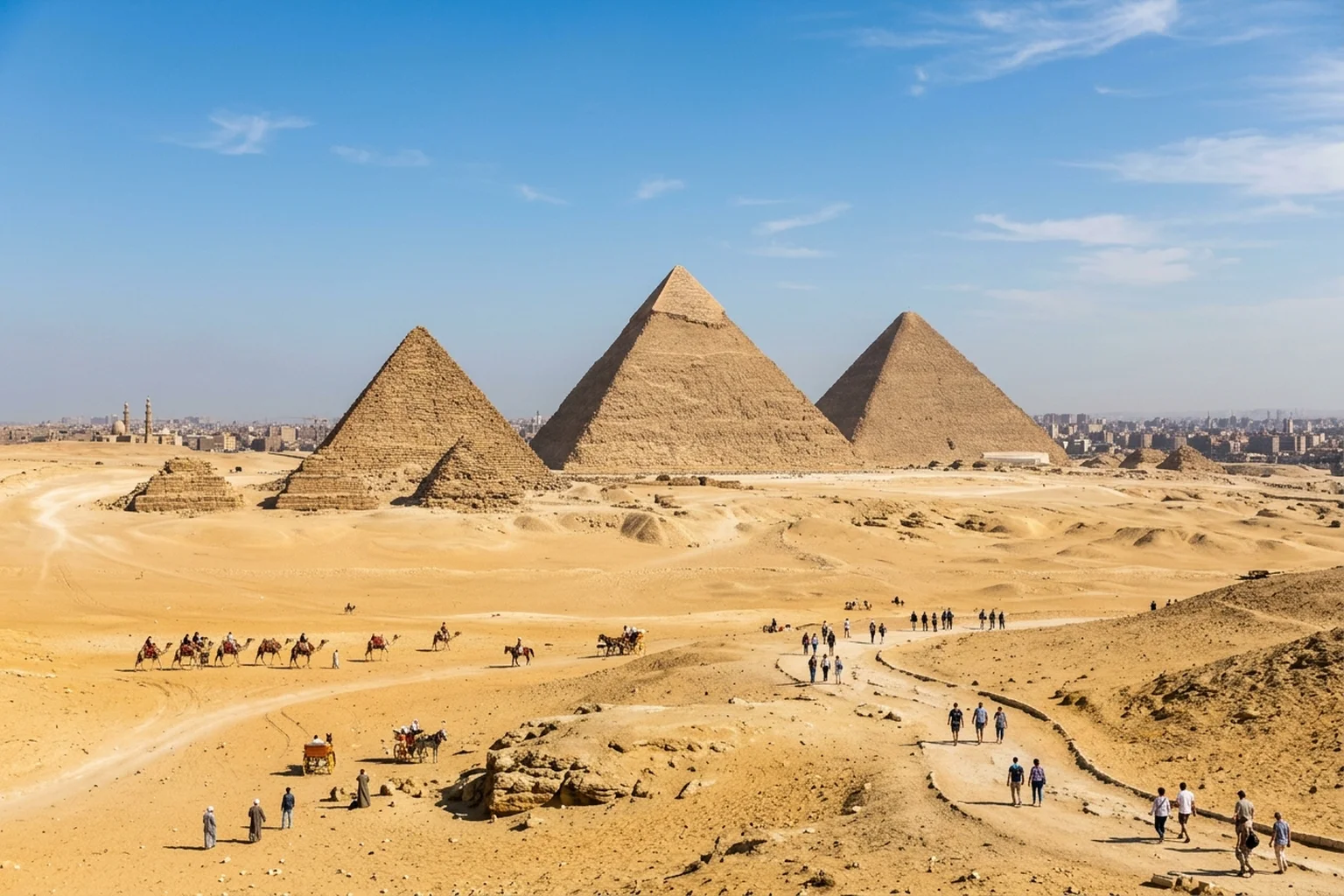 The Great Pyramids of Giza under a clear sky with visitors walking on designated desert paths